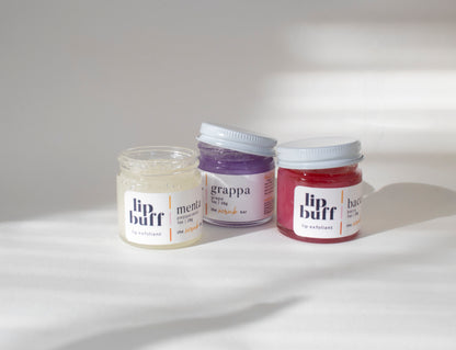 A trio of exfoliating lip scrubs from The Scrub Bar, including peppermint, grape, and berry. These handmade lip scrubs are perfect for exfoliating lips, revealing smoother skin while moisturizing with natural ingredients. Removing dry lip skin and hydrating it with lip oil. 