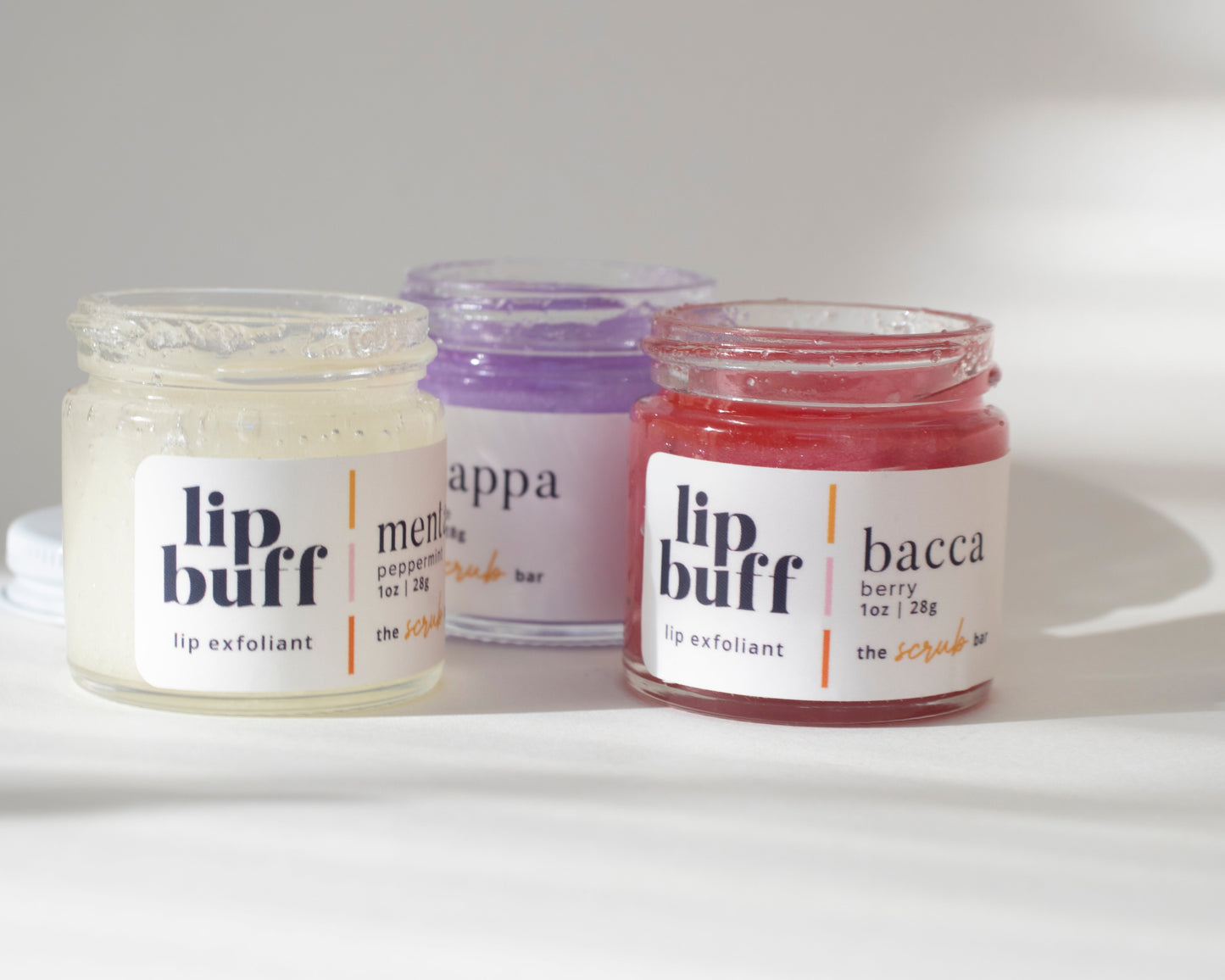 A trio of exfoliating lip scrubs from The Scrub Bar, including peppermint, grape, and berry. These handmade lip scrubs are perfect for exfoliating lips, revealing smoother skin while moisturizing with natural ingredients. Essential for your skincare routine.